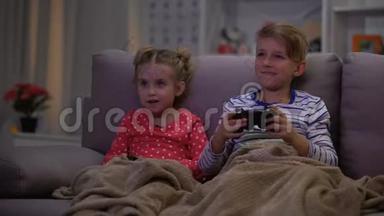 哥哥和姐姐开玩笑，用毯子盖被子，孩子们在玩网络游戏之夜